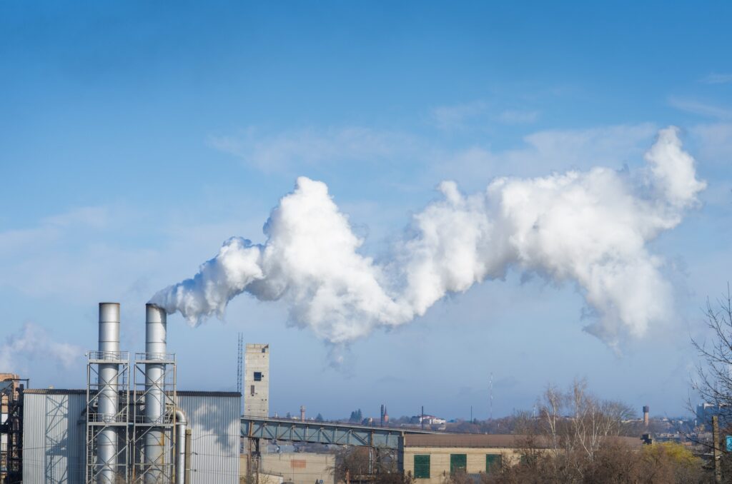 Chimney stalk with smoke on blue sky background. Environmental pollution