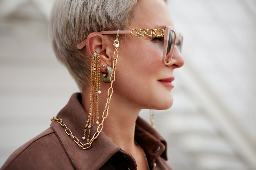 Close up portrait of woman wearing fashion accessories and jewelry, glasses on gold chain, earrings