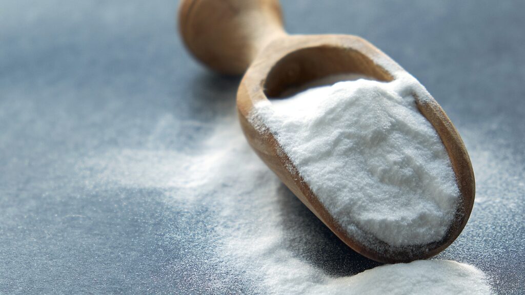 Glass bowl of baking soda. Spoonful of bicarbonate.