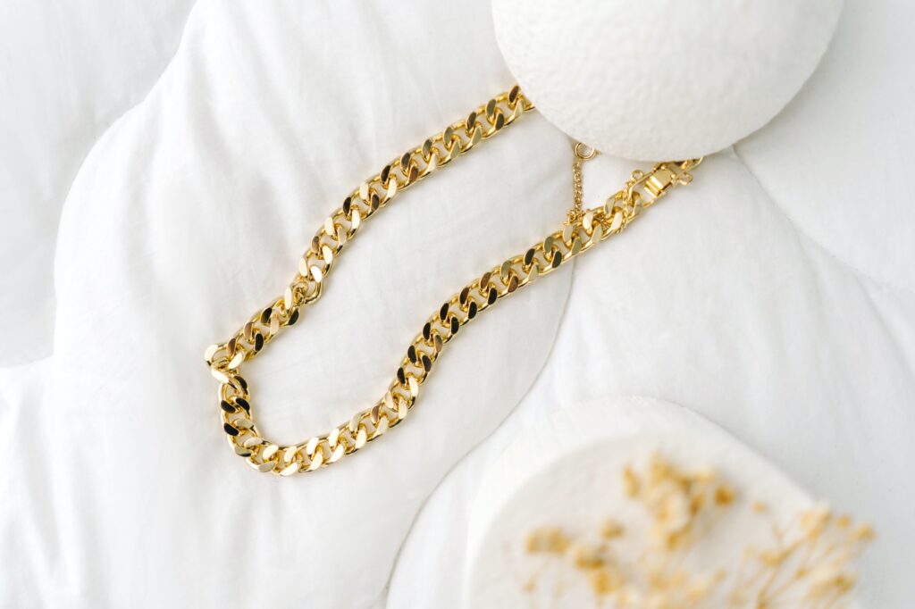 Golden modern bijouterie chain on white background.