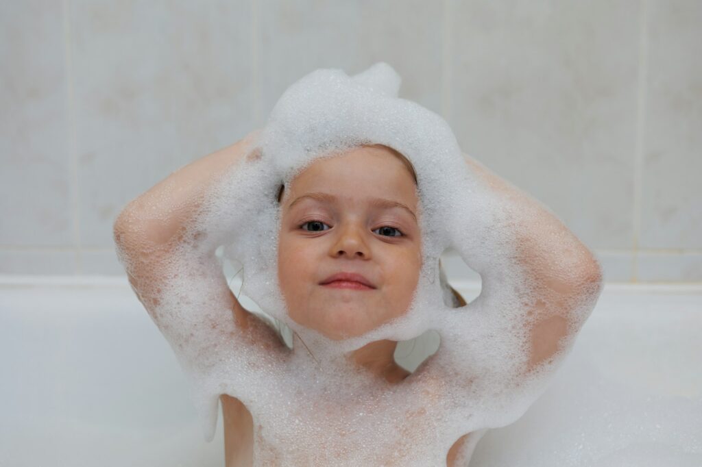 Little baby girl having bath with foam, smiling