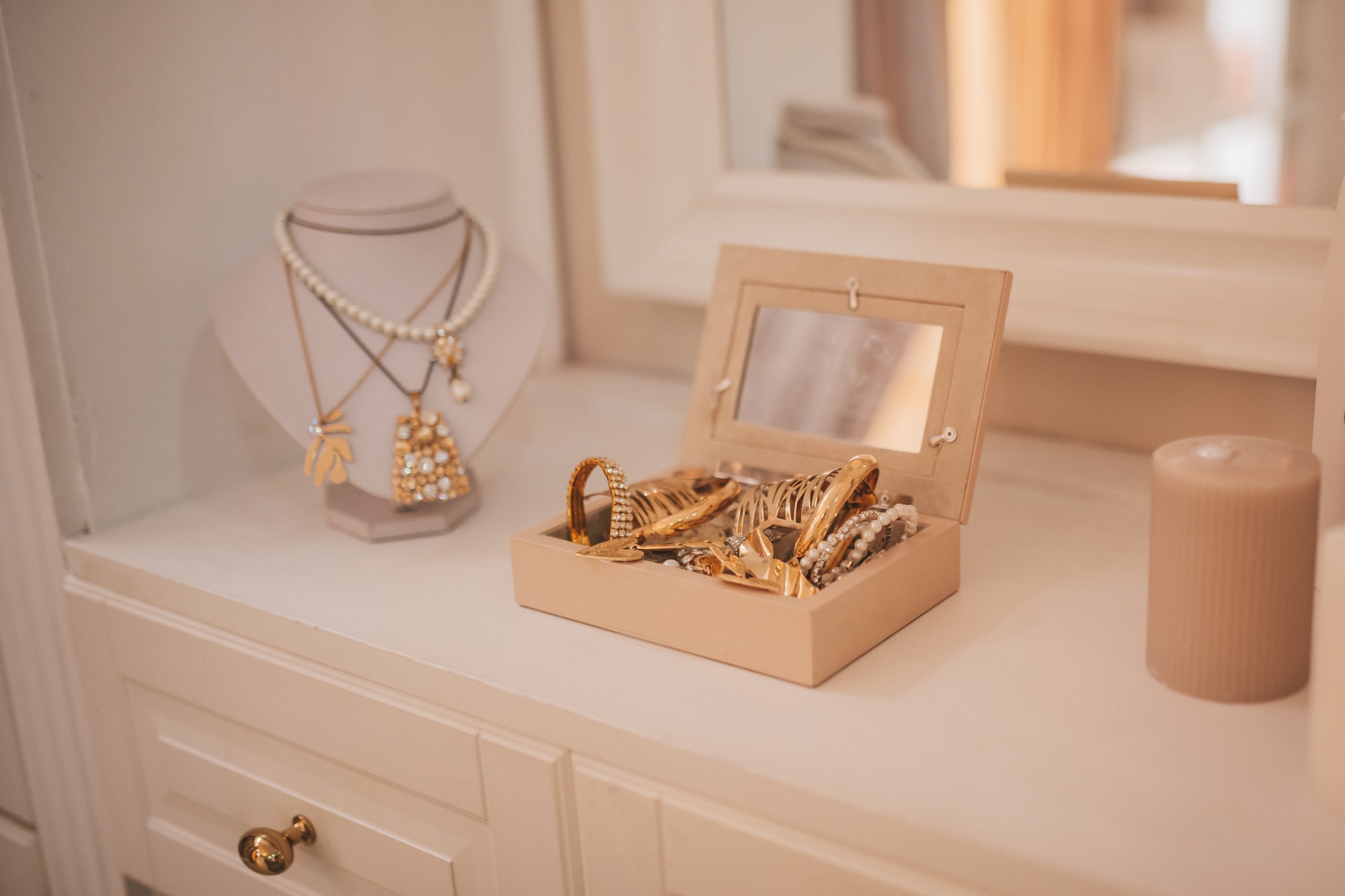 Luxury gold jewelry on set holders and in jewelry box on light dressing table and wardrobe shelves