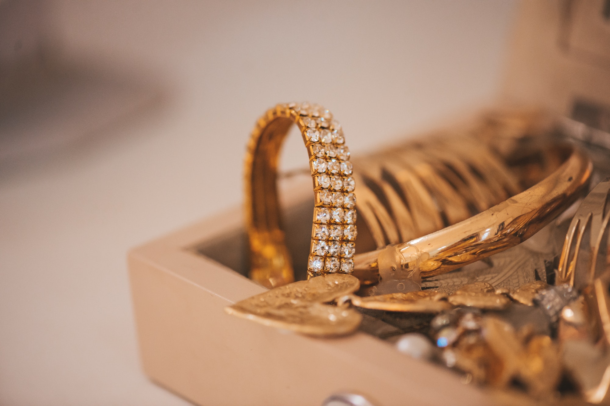 Luxury gold jewelry on set holders and in jewelry box on light dressing table and wardrobe shelves