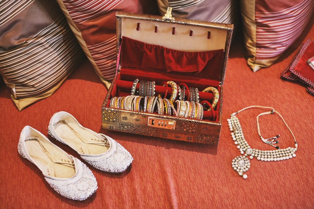 A collection of bangles or bracelets in the red box and white pump shoes and necklace of indian