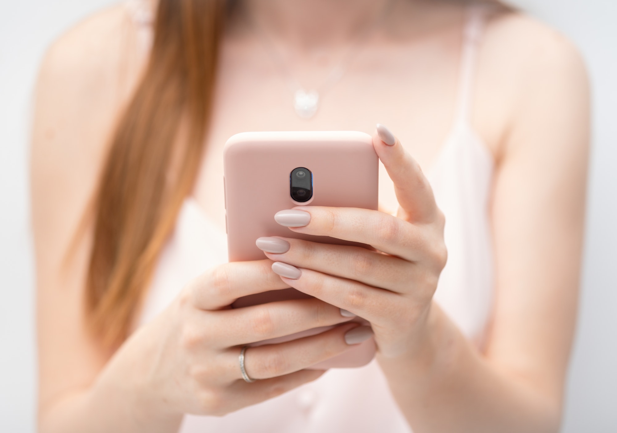 Female hands young woman using pink case smart phone