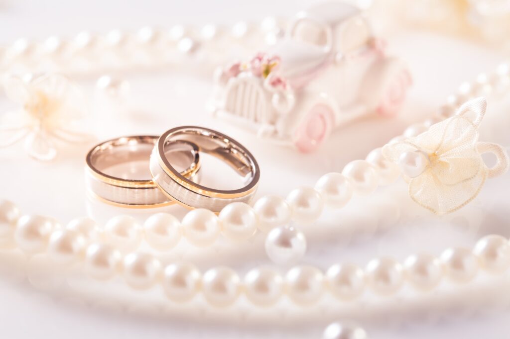 Wedding still life with golden rings and pearl necklace in white