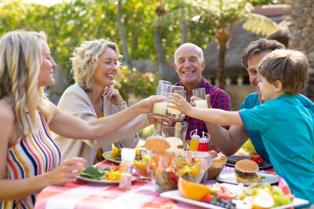 Happy caucasian three generational family toasting drinks at table in the garden