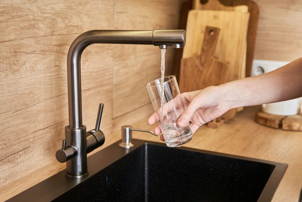 Woman pour clean water from tap filter into a glass