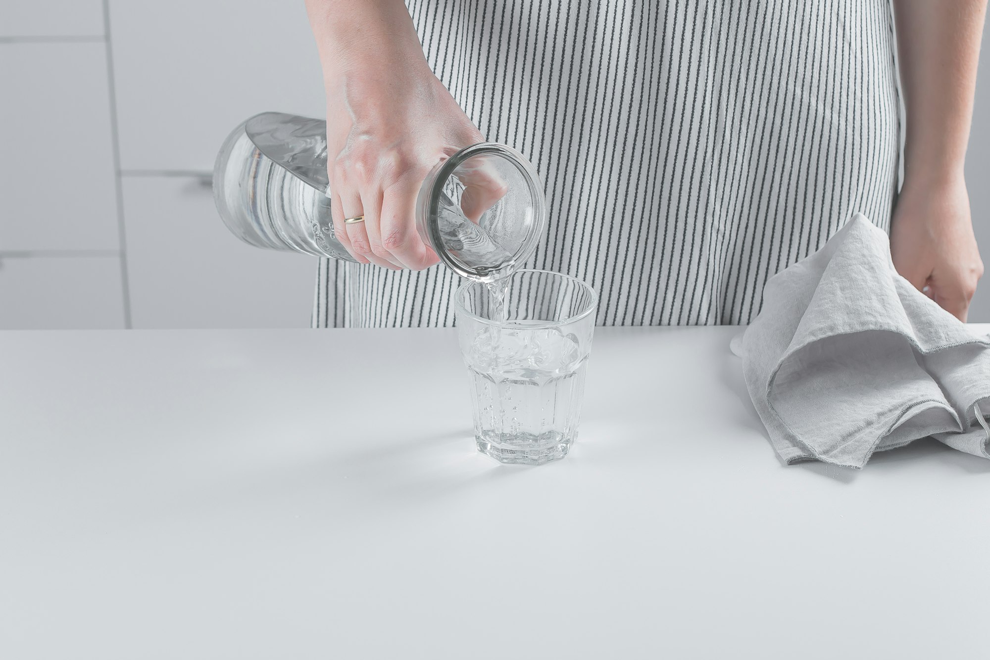 Woman pours clean drinking water from bottle to glass